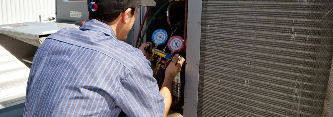 HVAC technician servicing a condenser unit in Oak Hill